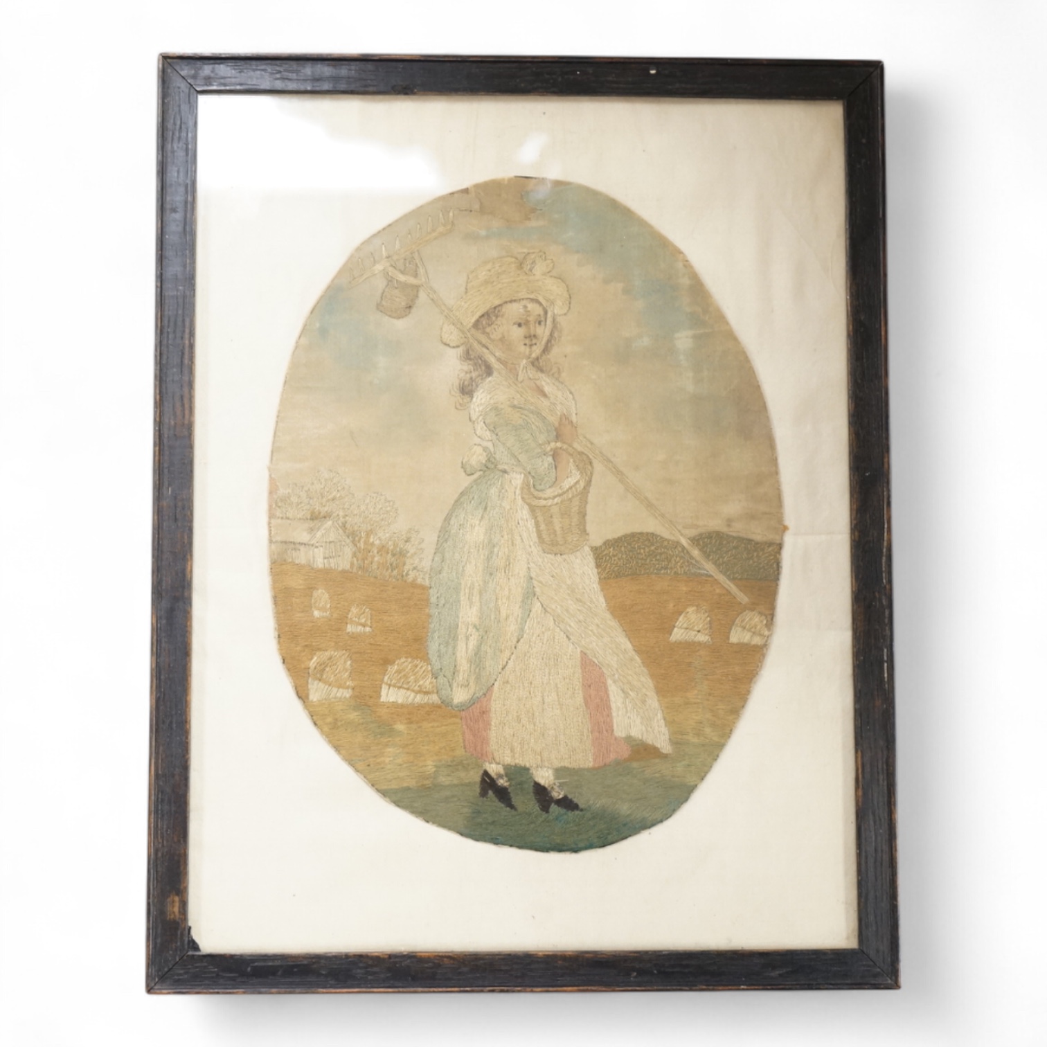 An 18th century coloured silkwork picture of a female farm hand, framed, 20cm high